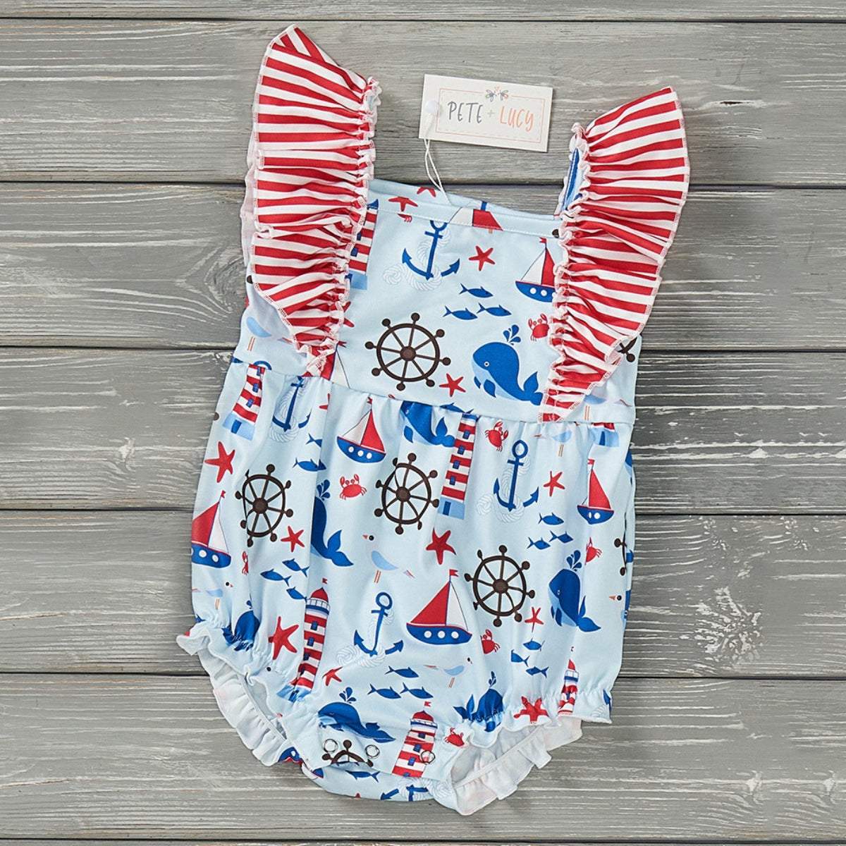 Nautical-themed girl romper with ruffle accents and anchor print.