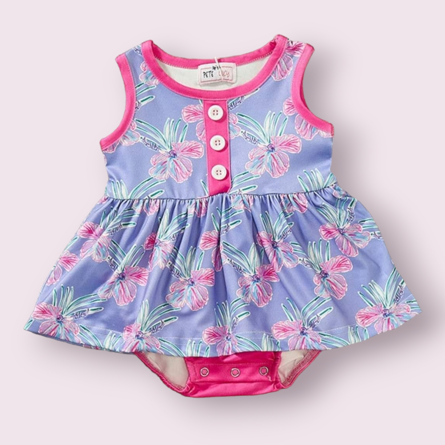 Paradise romper with vibrant floral design, sleeveless, pink accents, and button details.