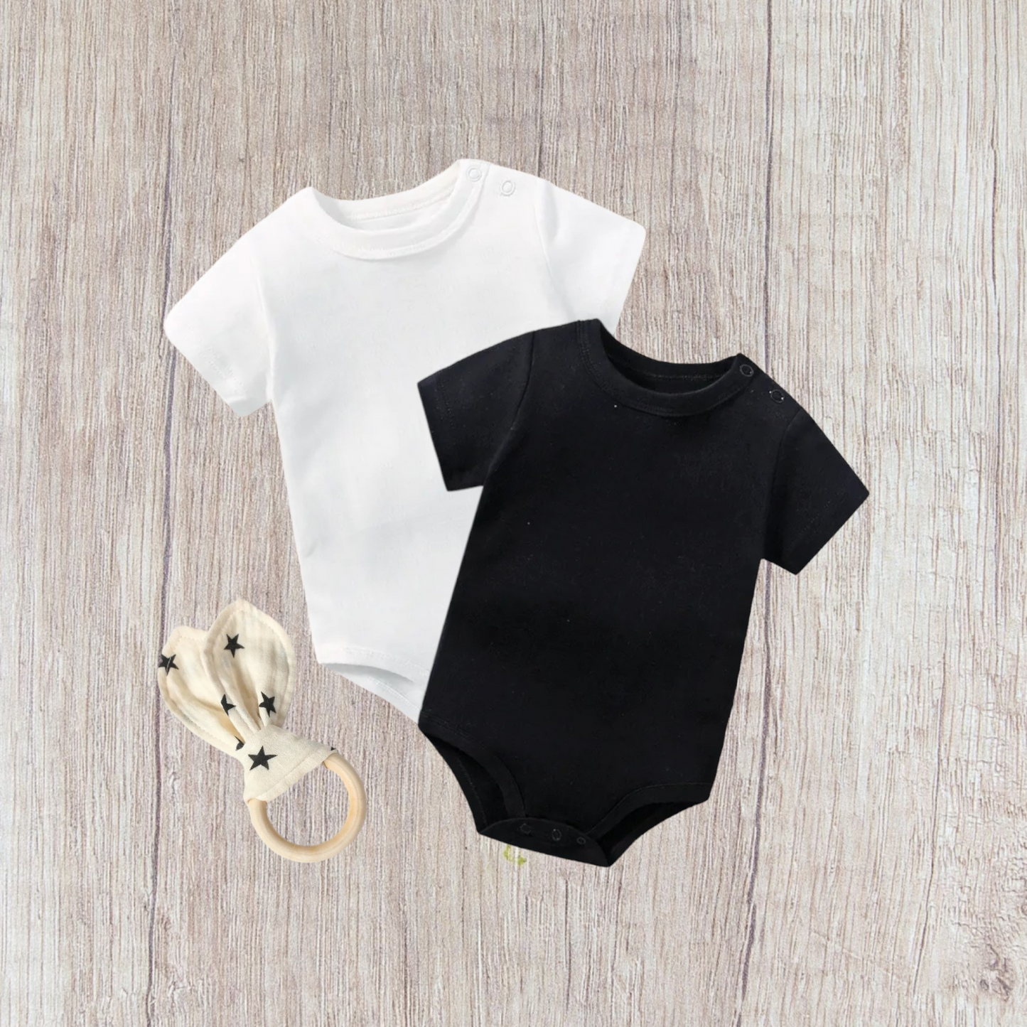 Baby bodysuit set with white and black bodysuits and rabbit ear teether.