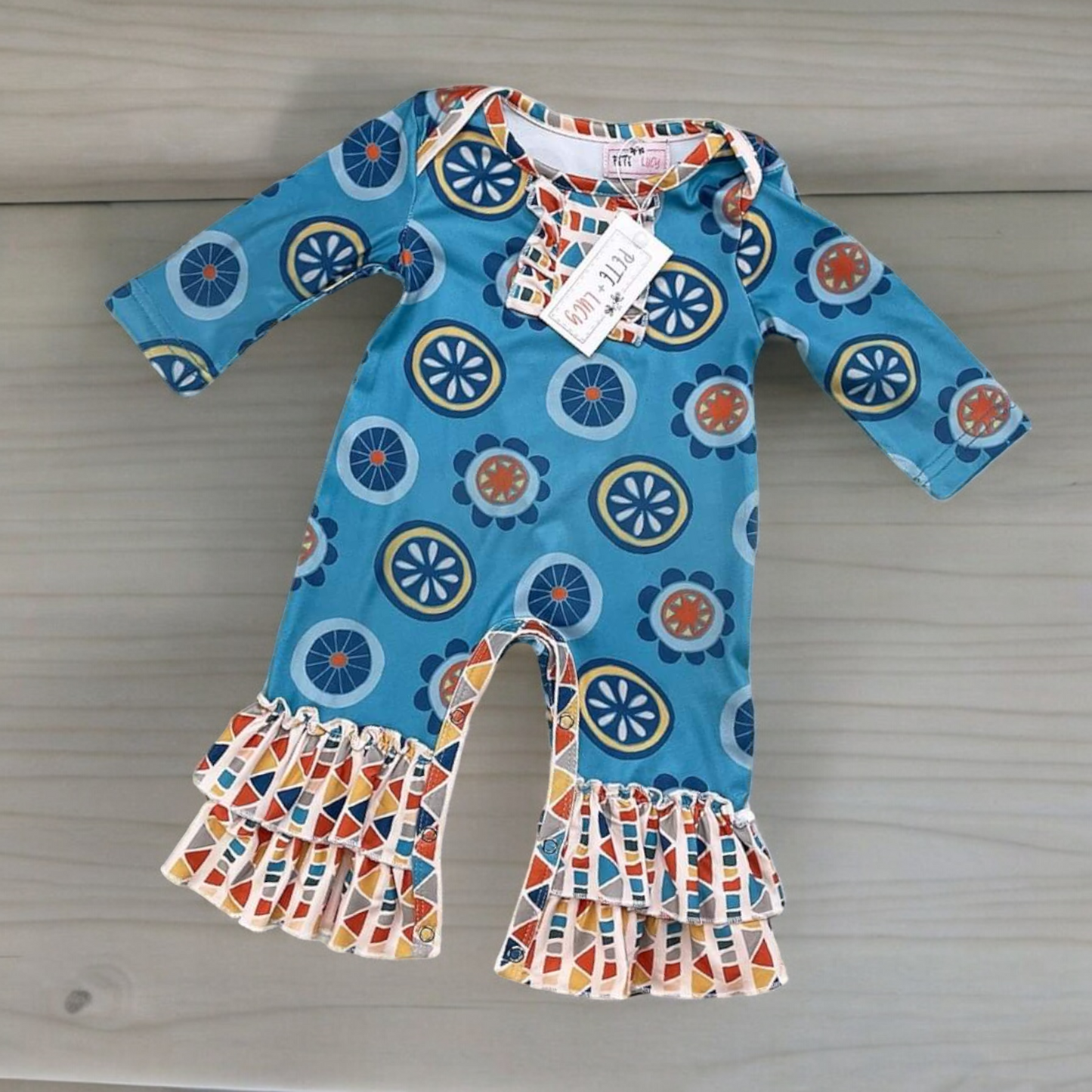Retro Geo Girl Romper with jewel neckline, long sleeves, and ruffle hem detailing.