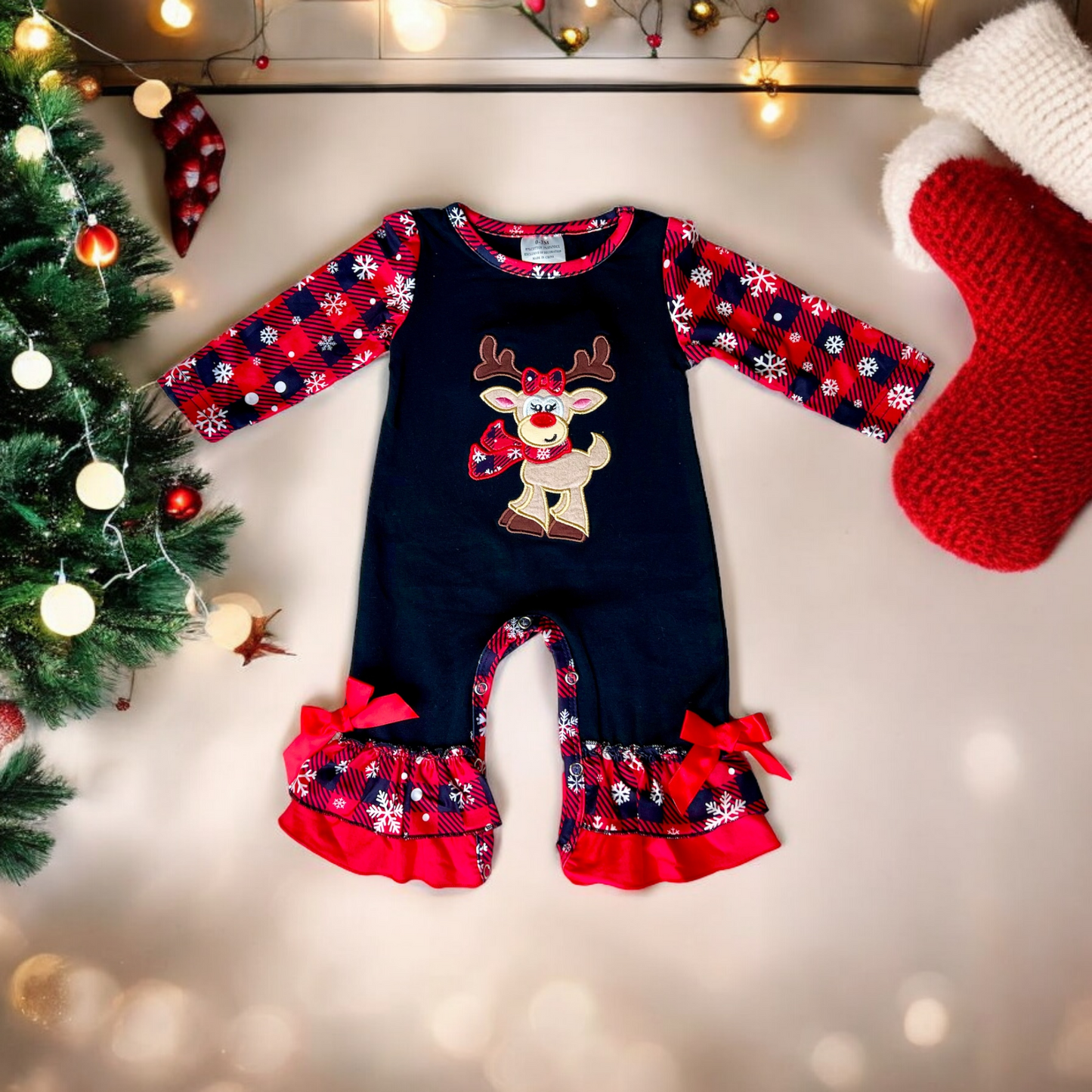 Baby girls Christmas plaid reindeer romper with snowflake plaid sleeves and ruffled pant legs decorated with red bows.