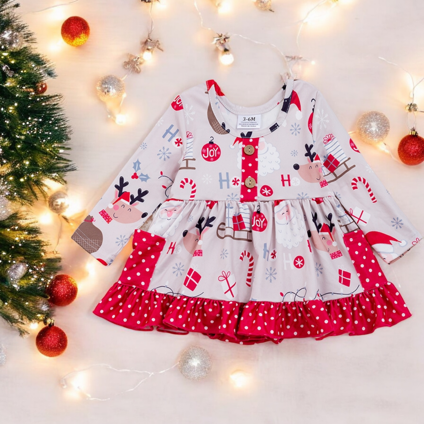 Festive Joy Christmas romper dress for babies with holiday reindeer and candy prints and red polka dot trim.