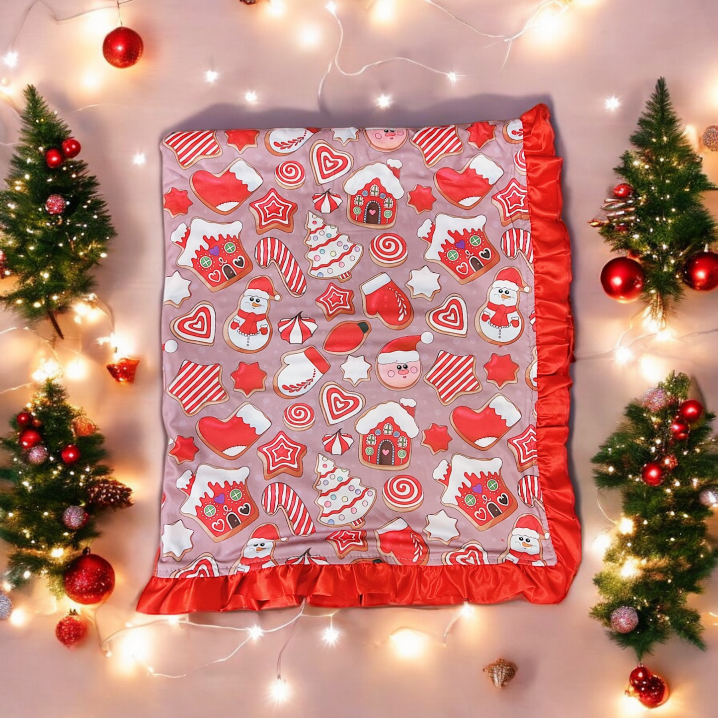 Sweet Christmas baby blanket with festive holiday prints and red satin trim surrounded by Christmas trees and lights