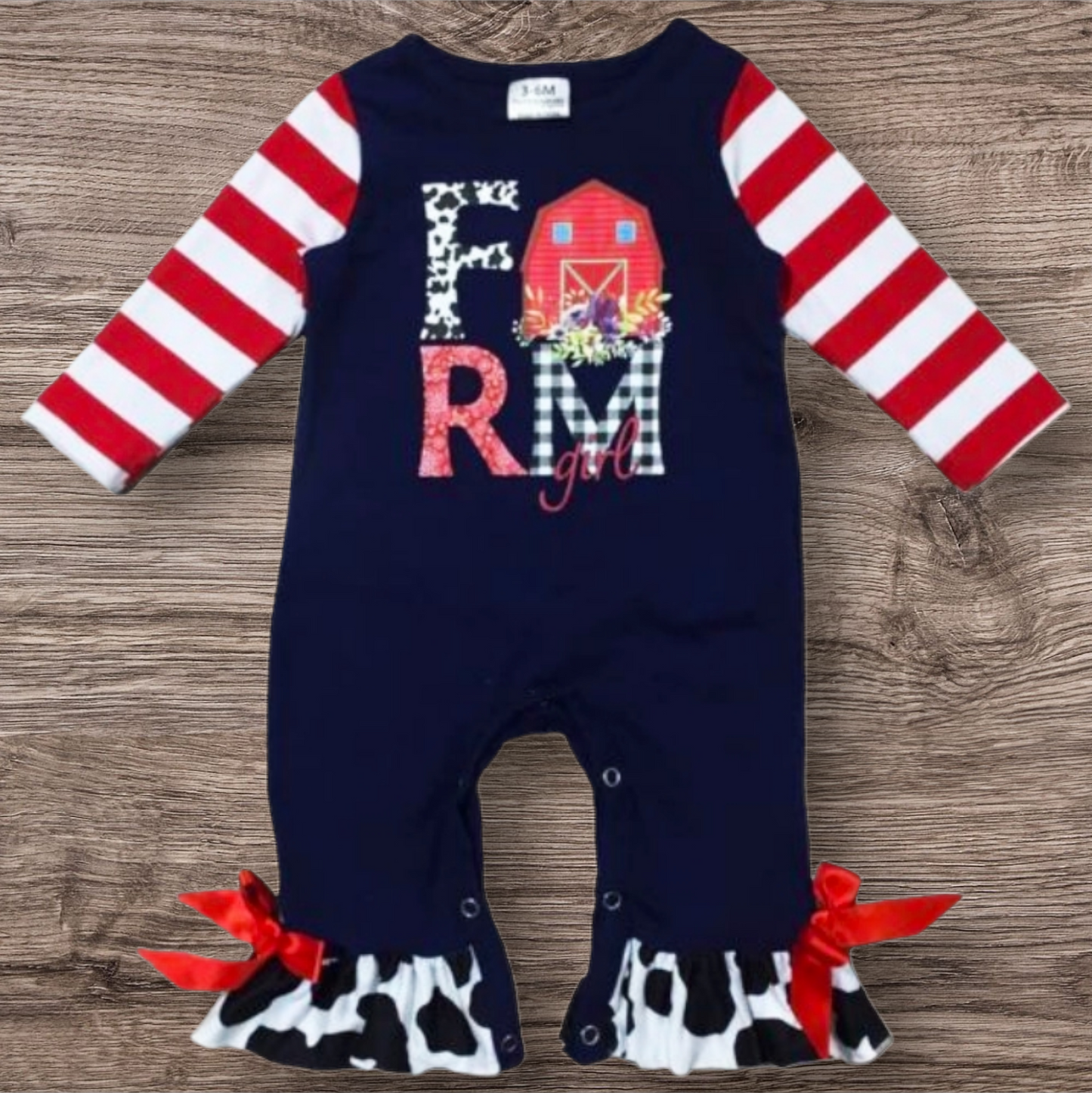 Farm Girl long sleeve romper with barn applique, red stripe sleeves, and cow print ruffle trim.