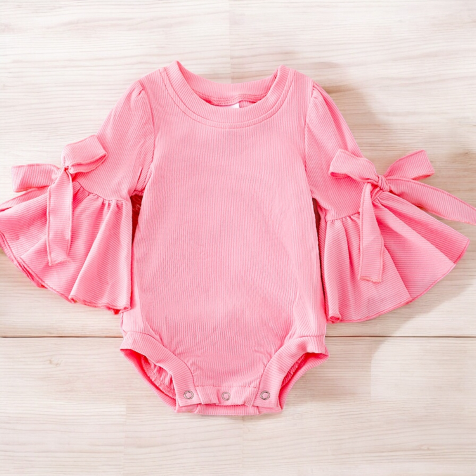 Pink bell sleeve onesie with snap closures.