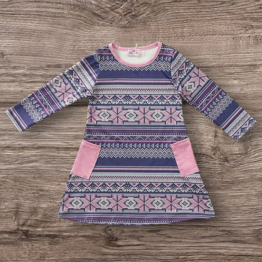 Nordic Frost Dress with Nordic pattern and pink accents on a wooden background.