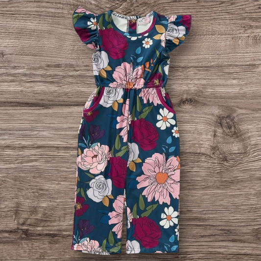 Floral Avery Jumpsuit with ruffled sleeves laying flat on wooden background.