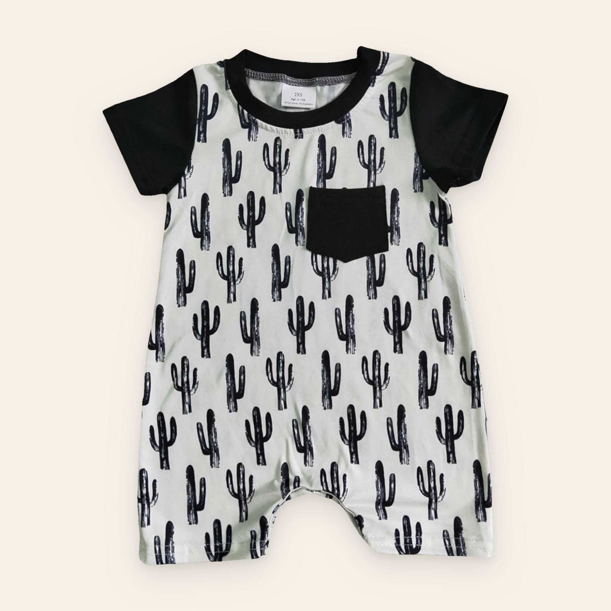 Black Cactus Romper with short sleeves and cactus print on wooden background.