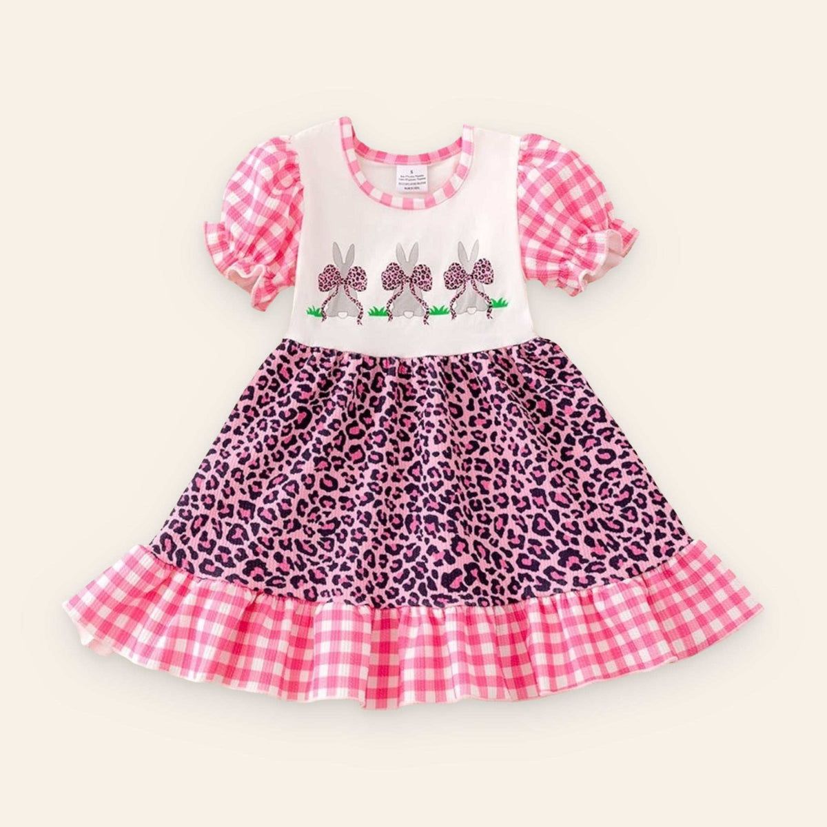 Little girl wearing pink cheetah Easter Bunny dress with gingham sleeves and ruffle hem
