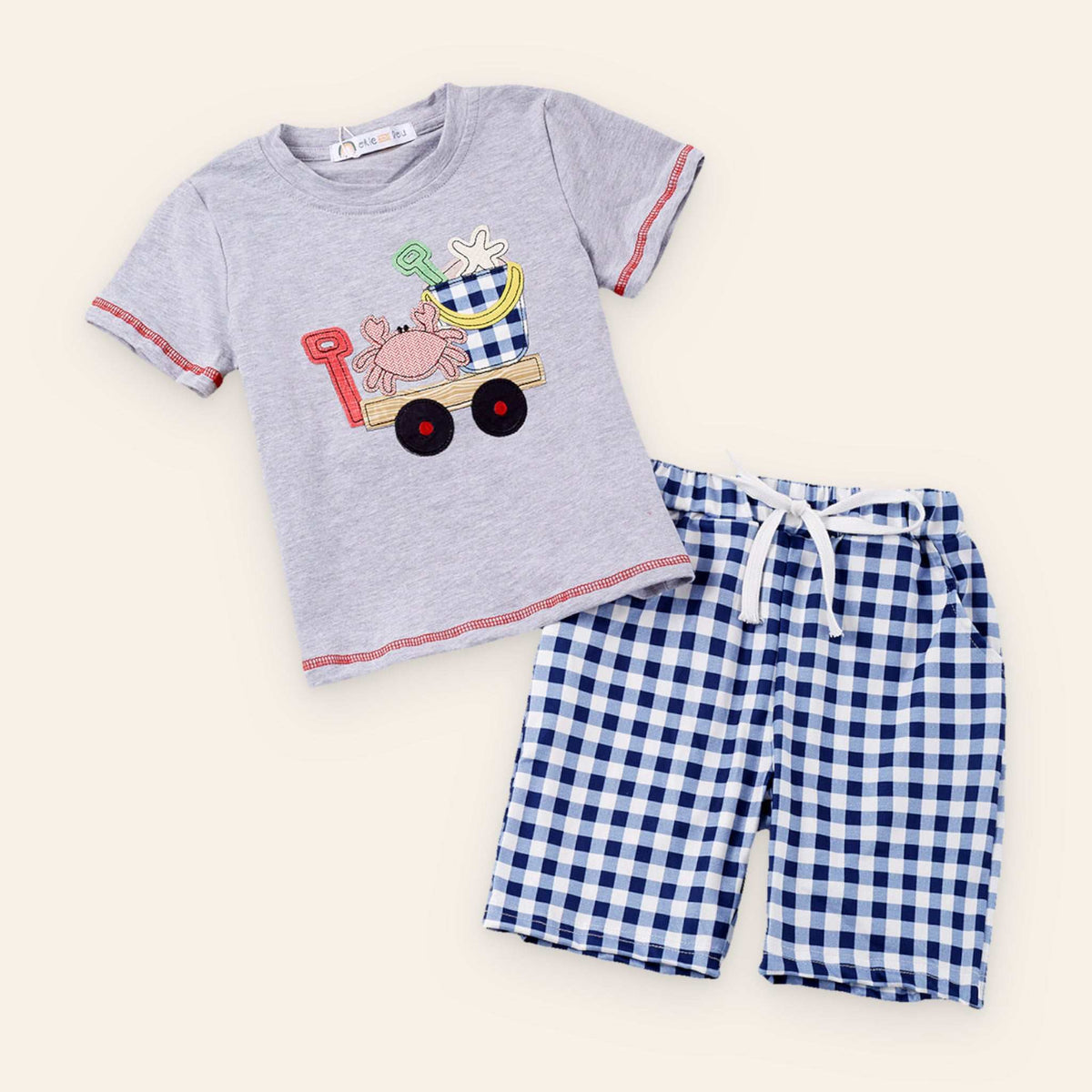 Boy's sand adventure outfit with a playful beach-themed gray top and blue checkered shorts.